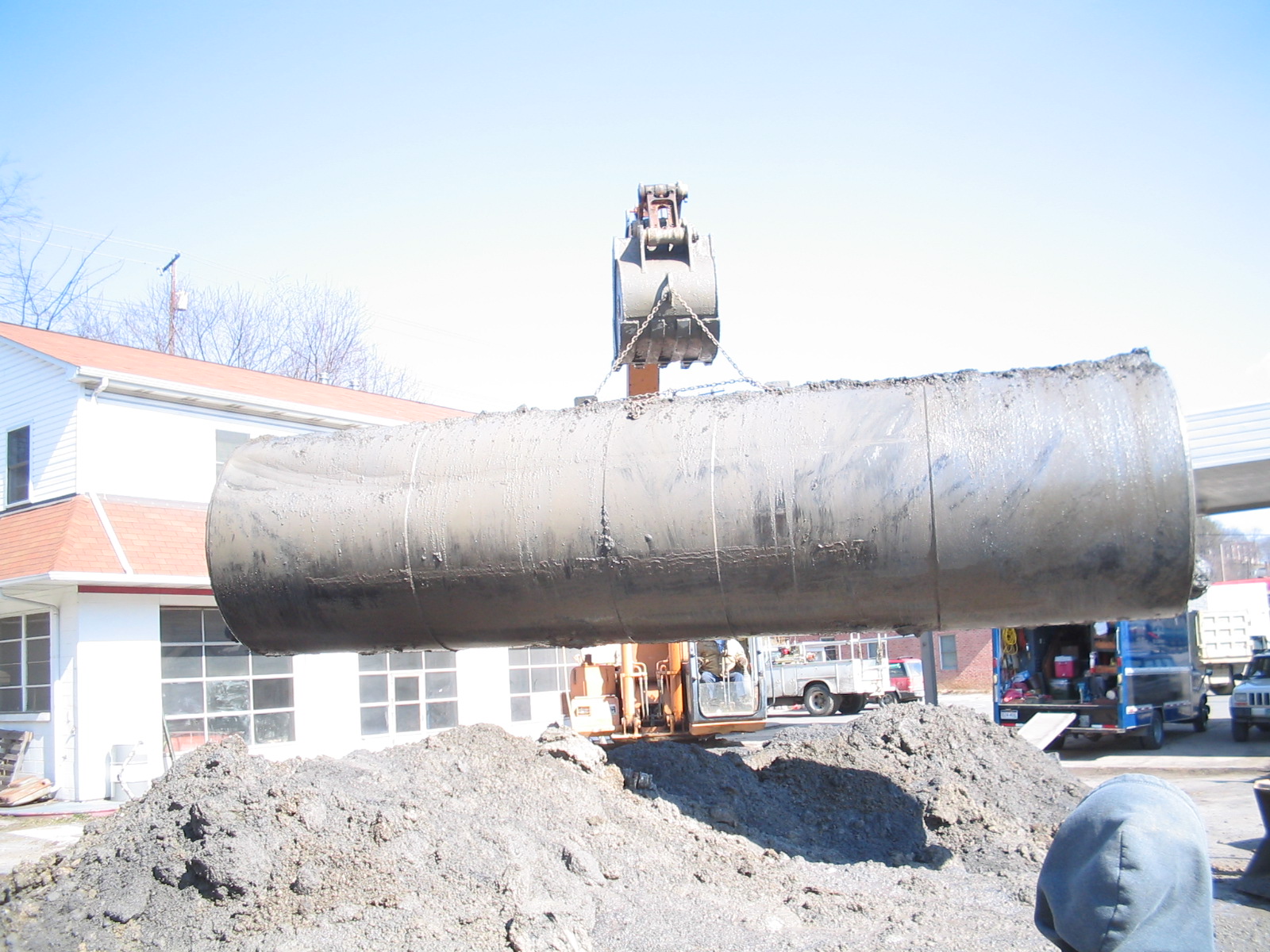 Backhoe lifting an underground storage tank