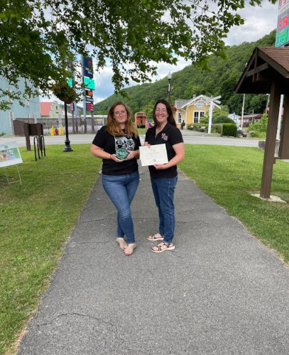 A Greenbank Public Library employee holds up a glass award, standing next to Beth Henry-Vance from the DEP's Youth Environmental Program.