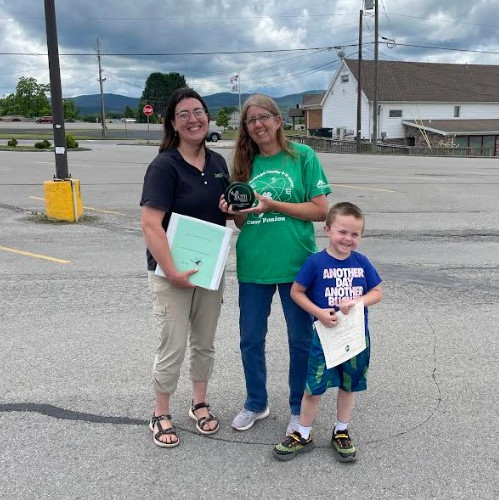 An adult leader and a youth from the Valley Livestock 4-H Club hold up their awards for a photo, standing next to Beth Henry-Vance of the DEP's Youth Environmental Program.